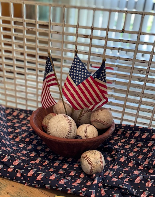 Dough bowl with flags & baseballs in front of wooden grate
