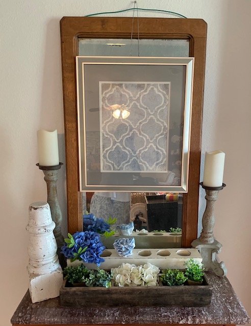 oak mirror over a marble topped chest with floral accents