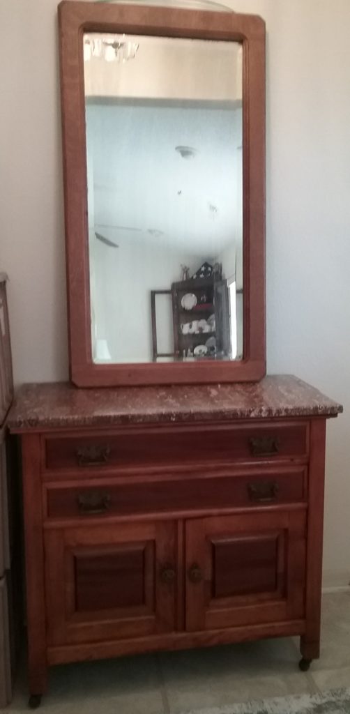 Oak framed mirror on top of marble topped chest