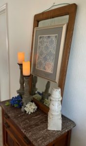 marble top chest with battery candles, silk flowers and a small architectual salvage piece