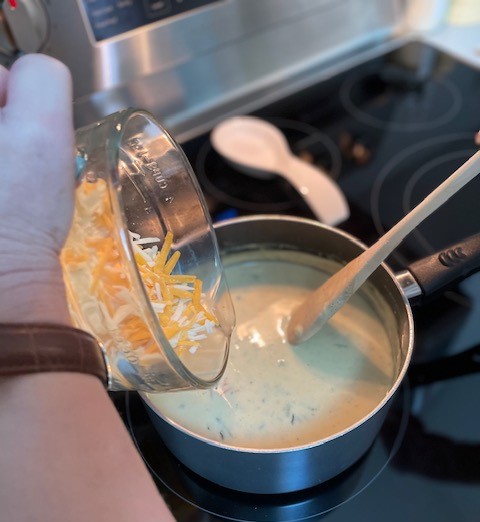 shredded cheese being added to soup