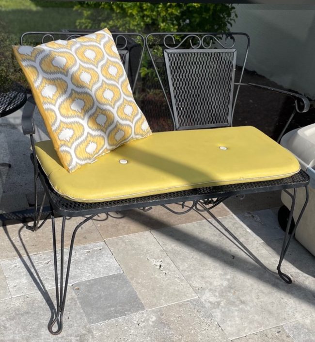 black wrought iron settee with yellow cushion