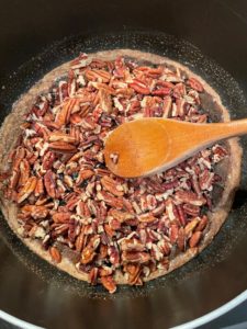 adding the pecans to the sugar syrup