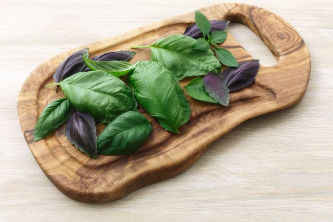 wooden cutting board with basil leaves