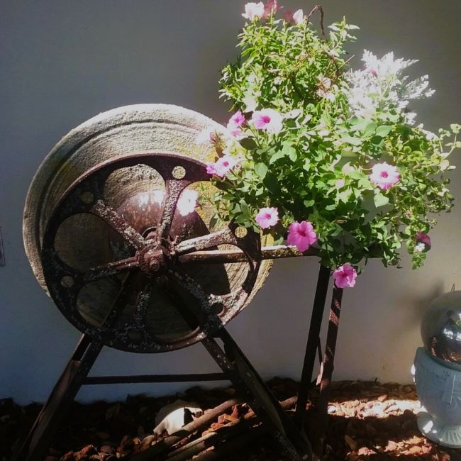 grindstone in the garden with a pot of pink flowers