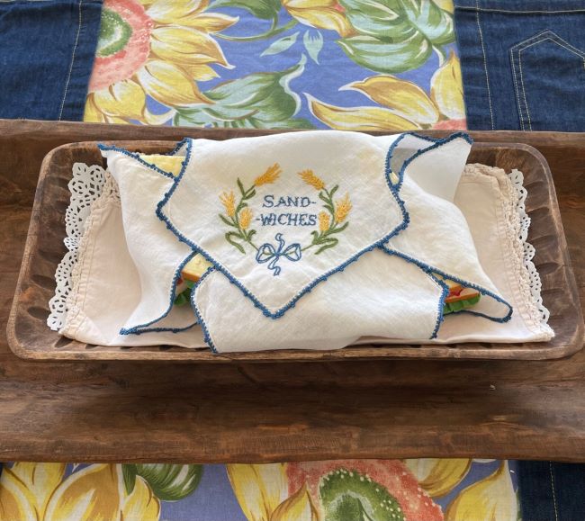 rectangle dough bowl with sandwiches wrapped in vintage linen