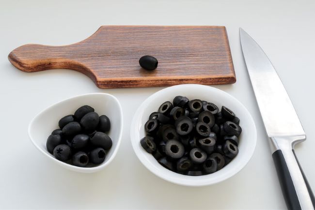 cutting board wit black olives and knife