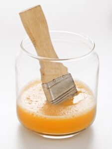 prepared egg wash in glass jar with a basting brush