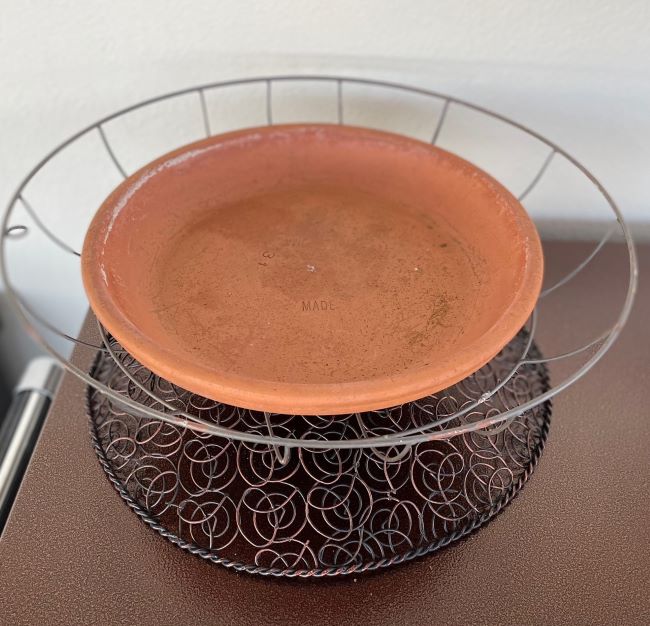 terra cotta saucer sitting in a wire fan cover