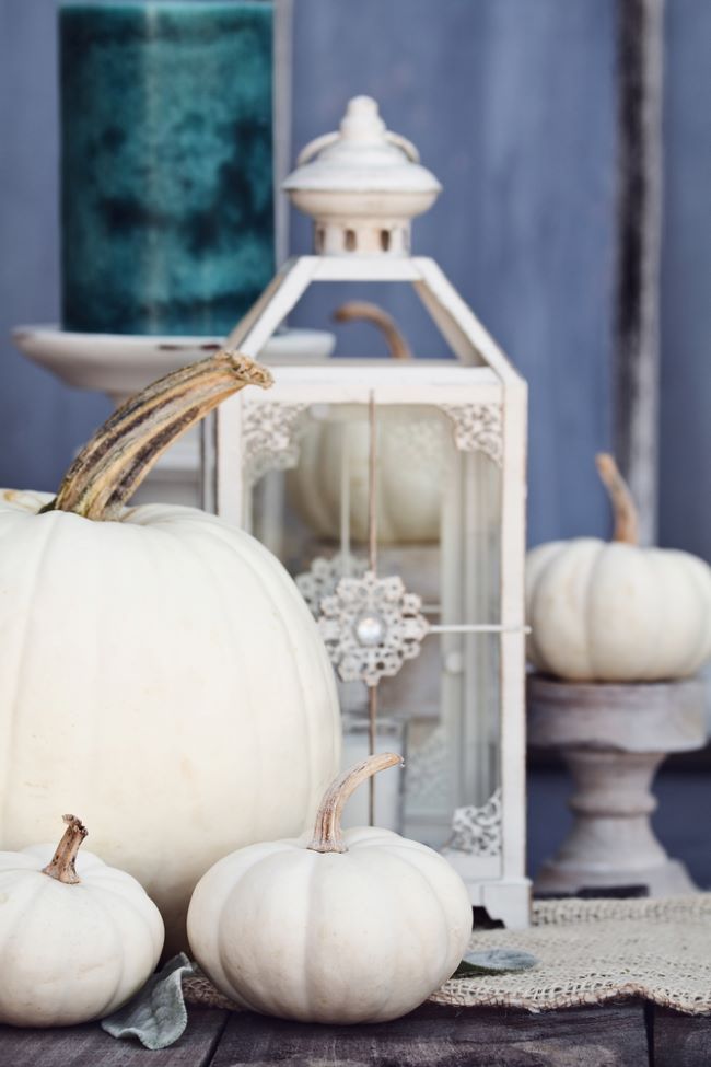 White metal lantern with wooden candle holders and white pumpkins