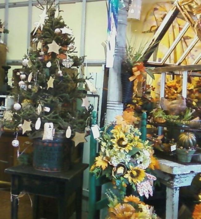 Primitive Christmas tree next to a Fall themed display in a flower shop
