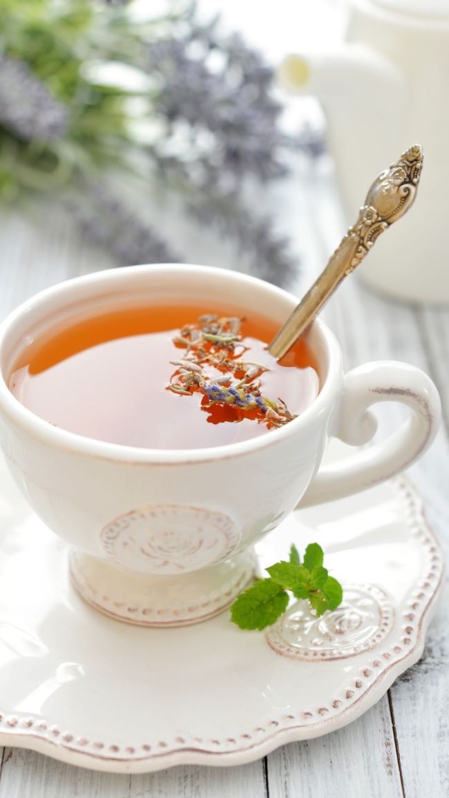 tea cup on saucer with herb tea and sprigs of lavender
