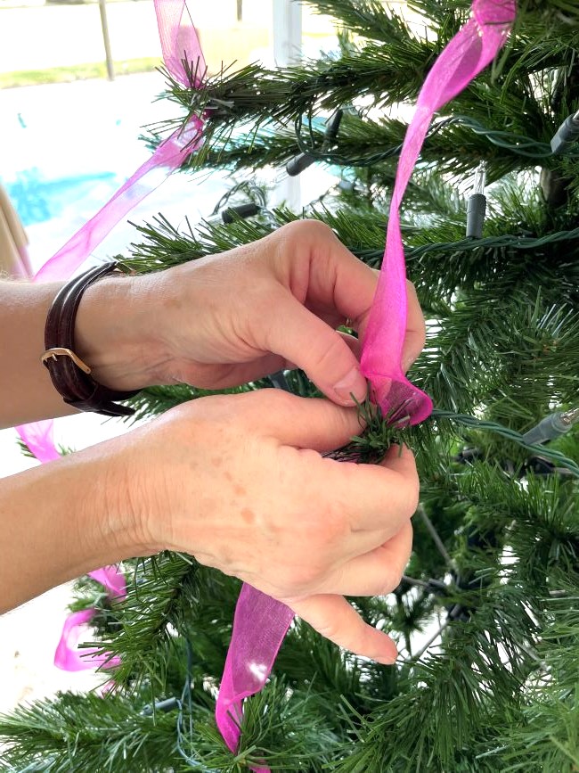 hot pink ribbon streamers being secured in the Christmas tree