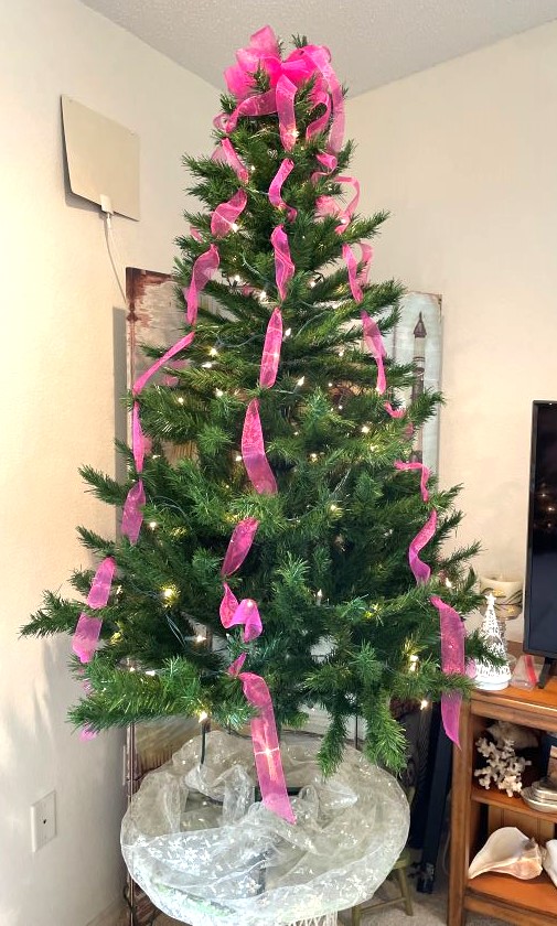 Christmas tree with lights and hot pink ribbon, ready to decorate