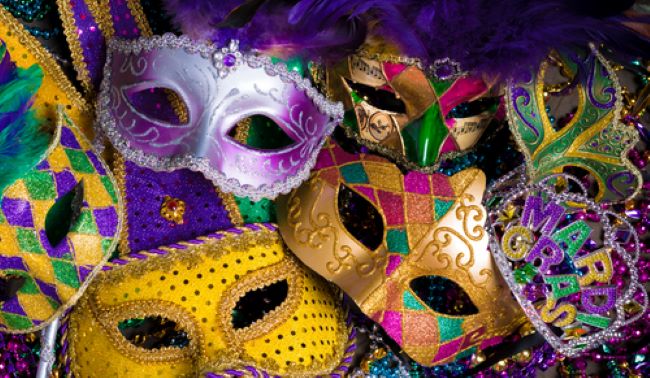 an assortment of Mardi Gras masks, a crown and multi colored beads