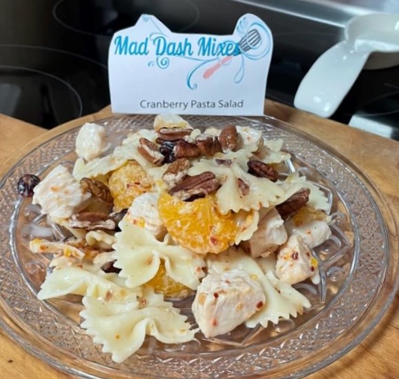 crystal plate with a serving of chicken pasta salad with mandarin orange slices, cranberries and pecans