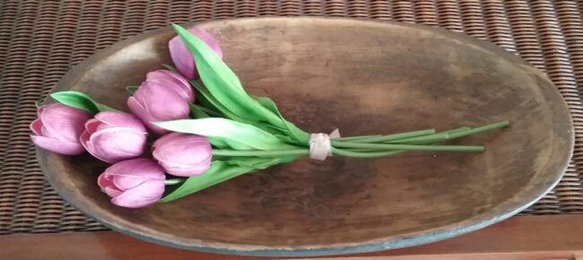 bouquet of faux purple tulips laying in an oval dough bowl