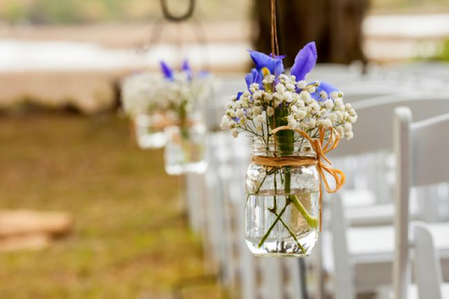 hanging mason jar with raffia bow, filled with baby's breath and a purple iris