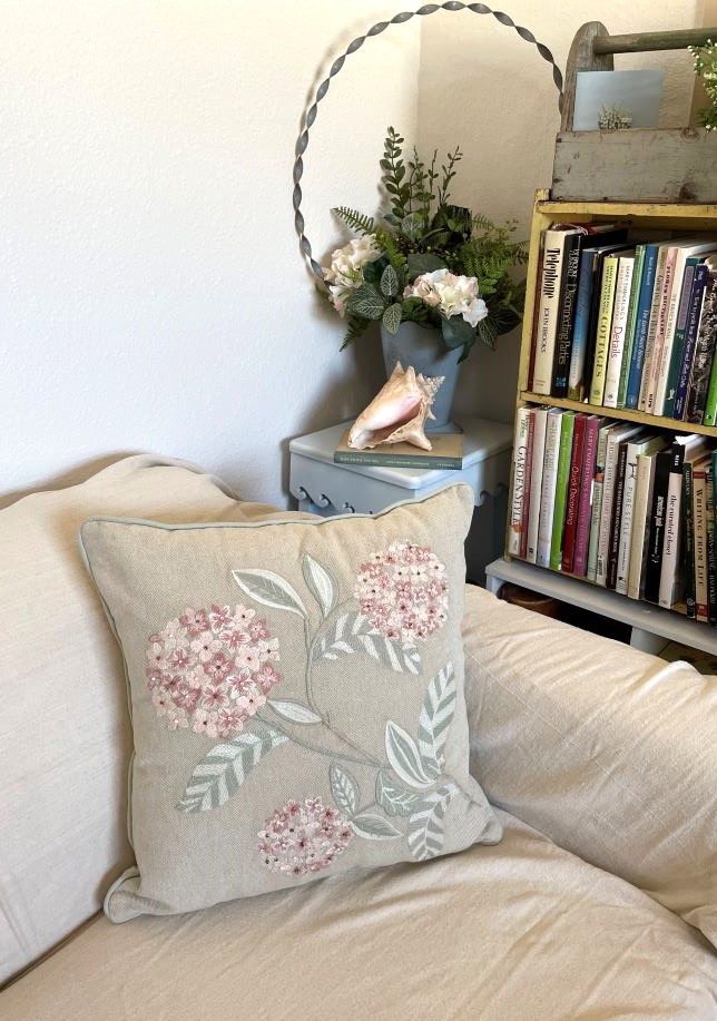 decorative throw pillow with a hydrangea design, displayed on a loveseat
