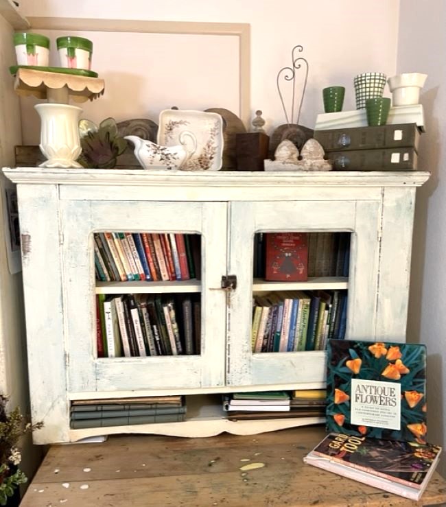 cream painted bookcase decorated with flea market finds