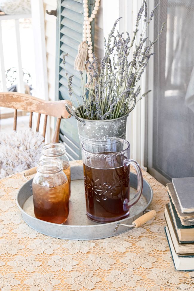 pitcher of iced tea and 2 mason jars full of tea on a round tray. Porch scene