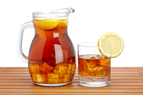 glass pitcher filled with iced tea & lemon slices
