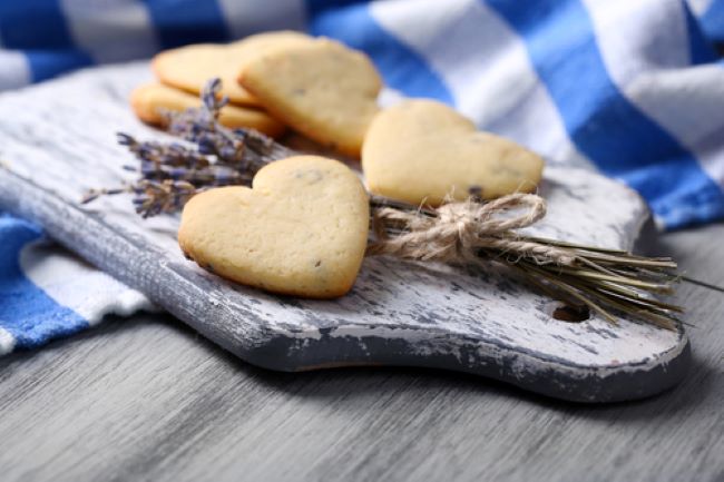 old cutting board with heart shaped shortbread cookies and a sprig of lavender