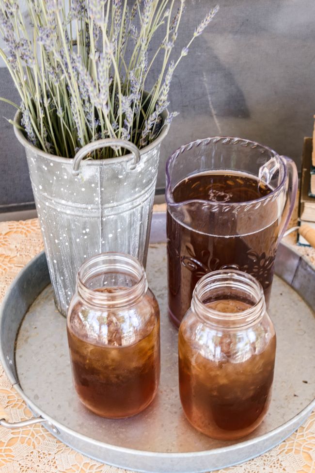 galvanized tray with ice tea in a pitcher, two mason jars and a bucket of lavender
