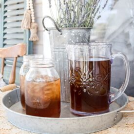 close up view of galvanized tray holding a pitcher of iced tea and two mason jars of tea accented with a bucket of french lavender