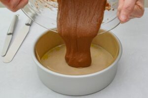chocolate cake batter being poured into round cake pan