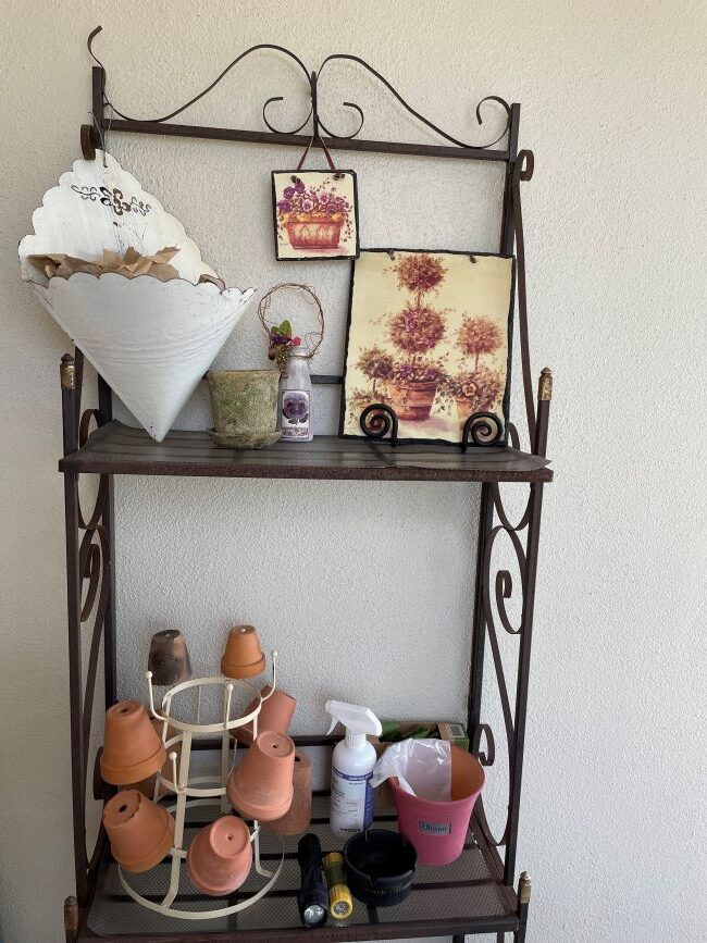 wrought iron display shelf with terra cotta pots and barn tin wall pocket