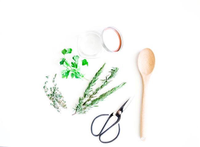 sprigs of thyme, rosemary, parsley with scissors and a wooden spoon