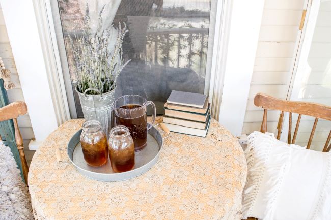 lace covered table with two chairs and Iced tea on a porch