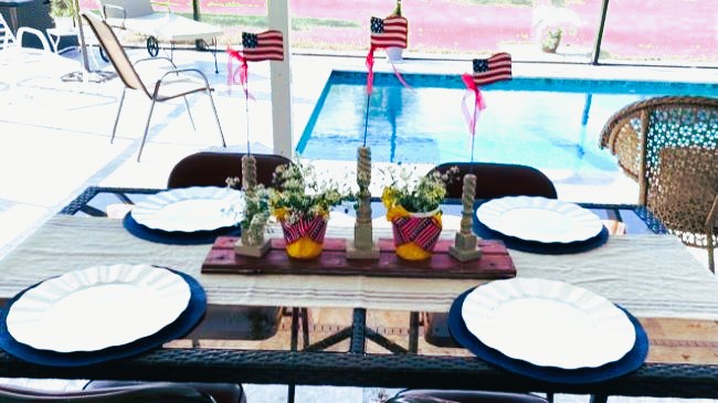 rustic inspired Summer centerpiece with patriotic spindles and flowering plants