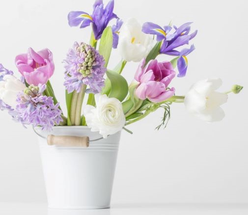 mixed bouquet of iris, tulips, and hyacinth in a white metal bucket