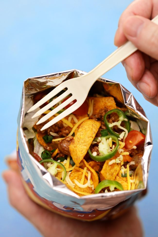 close up of a Walking Taco - taco meat & toppings served in a small bag of corn chips