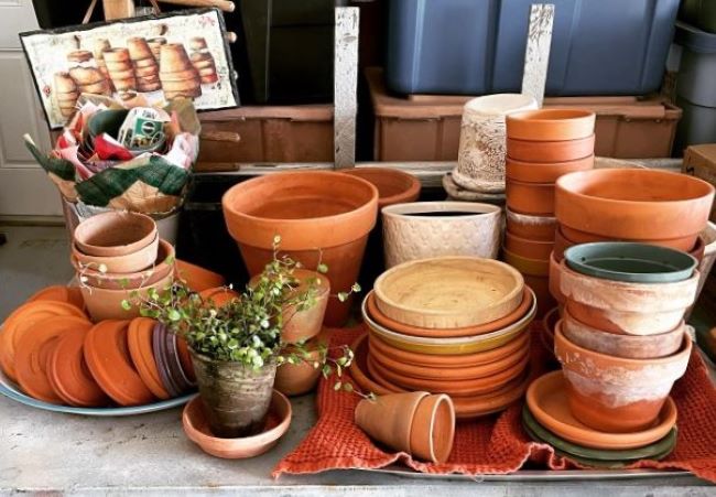 assorted terra cotta pots and saucers displayed on old table