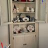 chalk painted corner hutch decorated with restaurant china & blue delft
