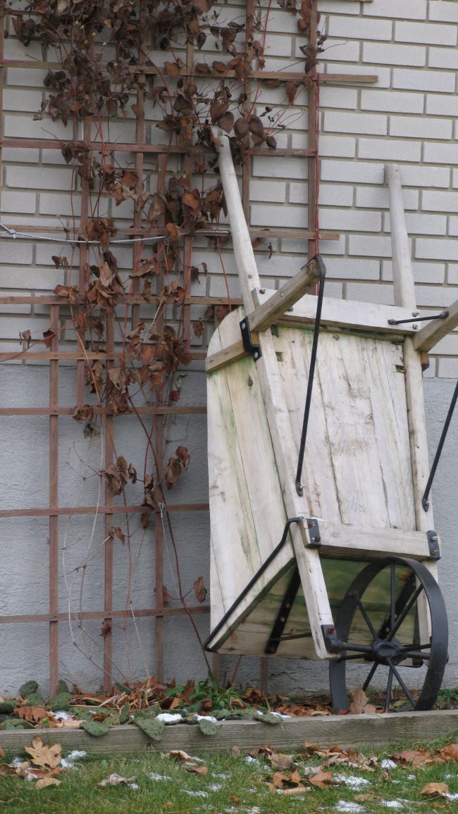 wooden wheelbarrow leaning against a building