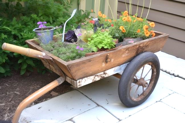 wooden wheelbarrow filled with various containers of plants
