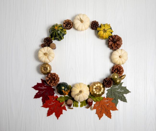 white pumpkins, gourds, pine cones and leaves displayed in a circle