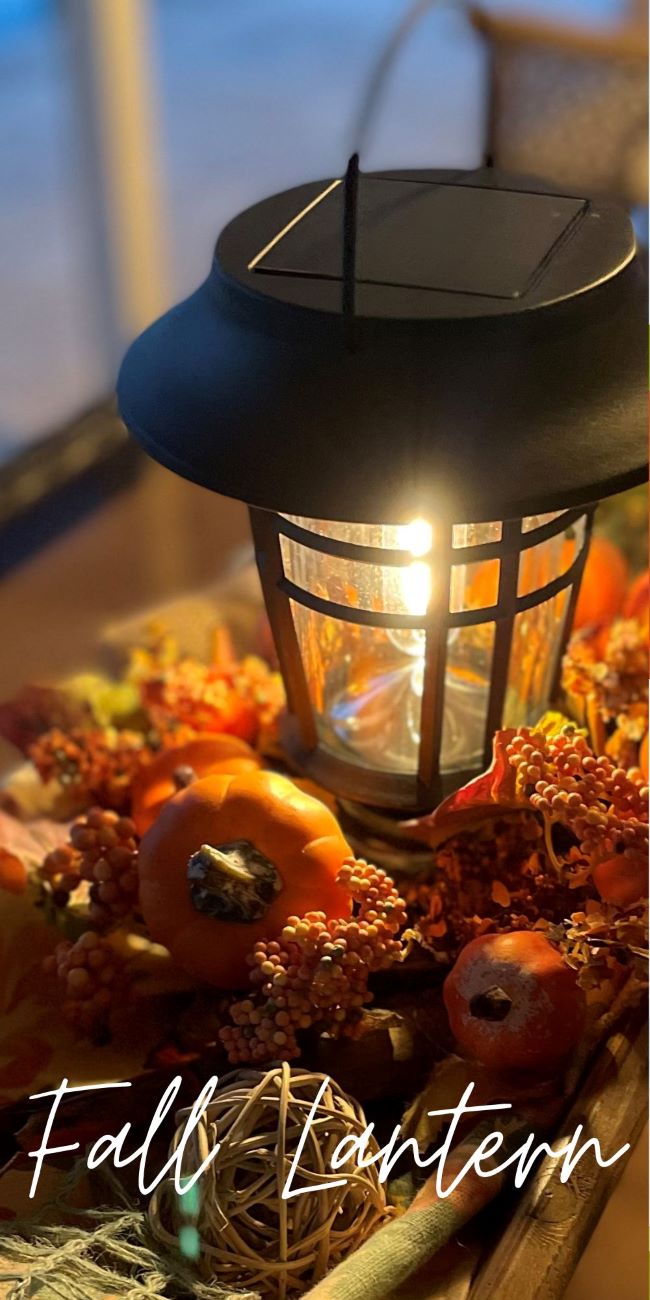 solar lantern nestled in a wooden tray accented by faux pumpkins