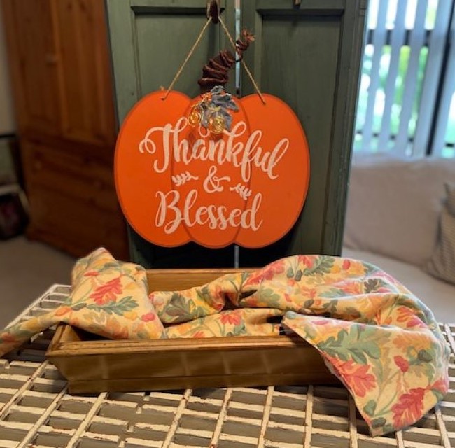 pastel colored fall fabric placed in a low wooden tray. The start of an Autumn vignette