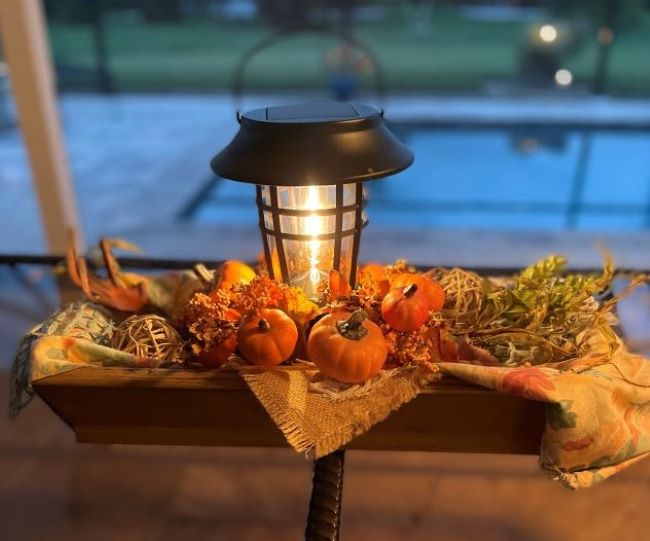 solar lantern nestled in a low wooden bowl, accented with fall botanicals