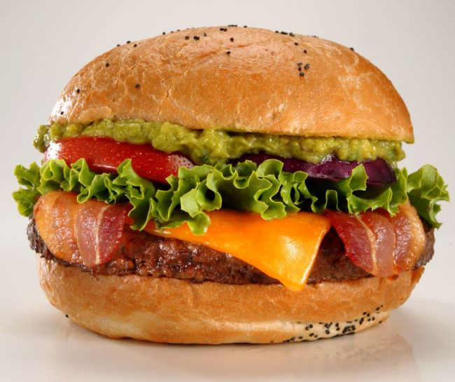 hamburger topped with bacon, cheese, lettuce, tomato, onion and guacamole
