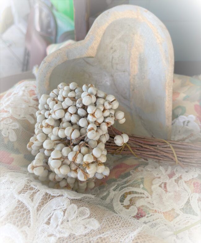 bundle of dried tallow berries nestled in front of a small wooden heart bowl