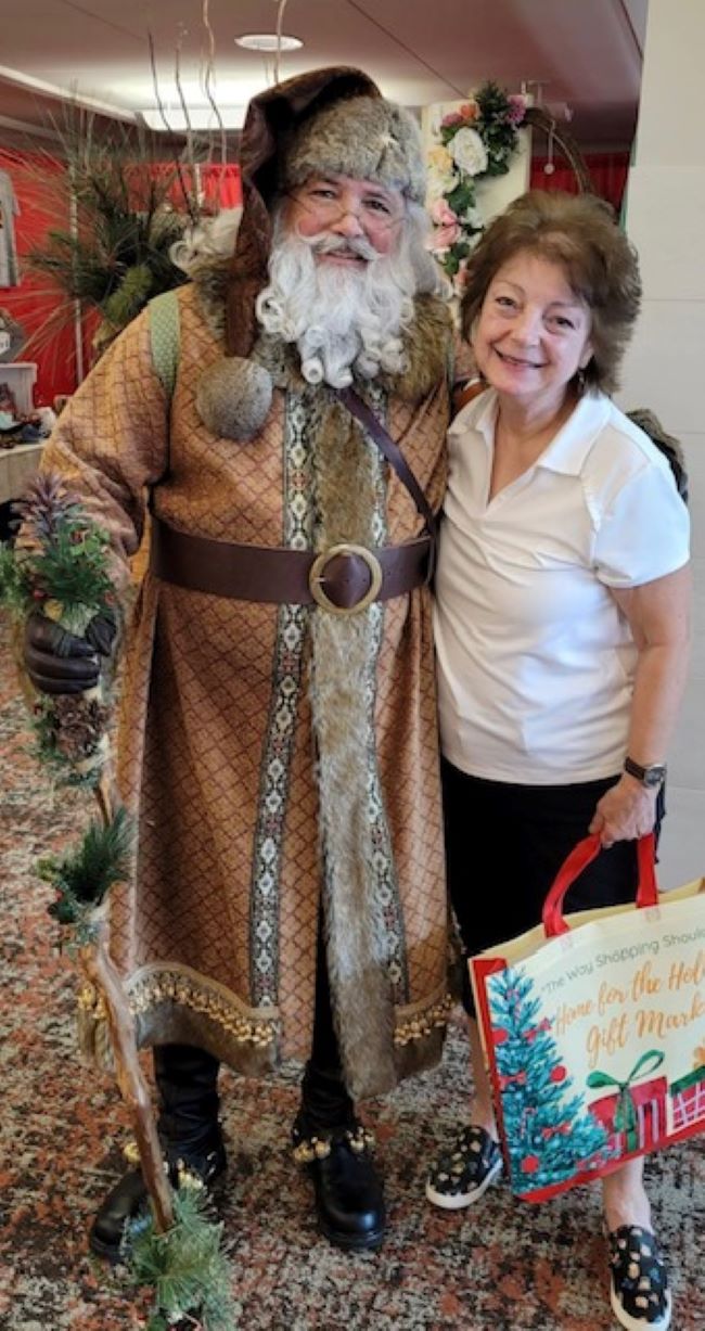 Old World Santa posing with a woman at a craft fair