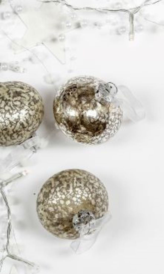 trio of silver Christmas ornaments on a white background