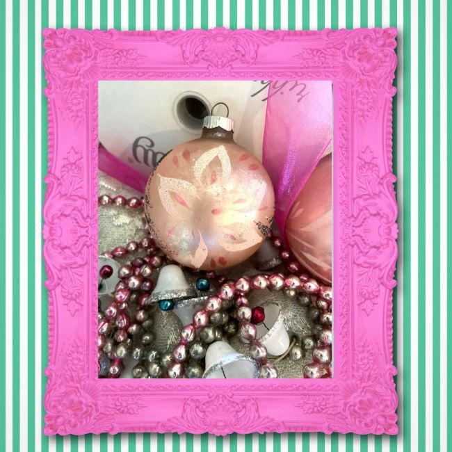 hot pink frame surrounding a vignette of pink glass ornaments, vintage beaded garland and hot pink ribbon
