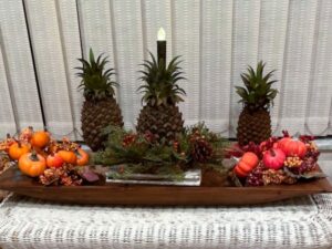 faux pineapple and pumpkins in a wooden dough bowl